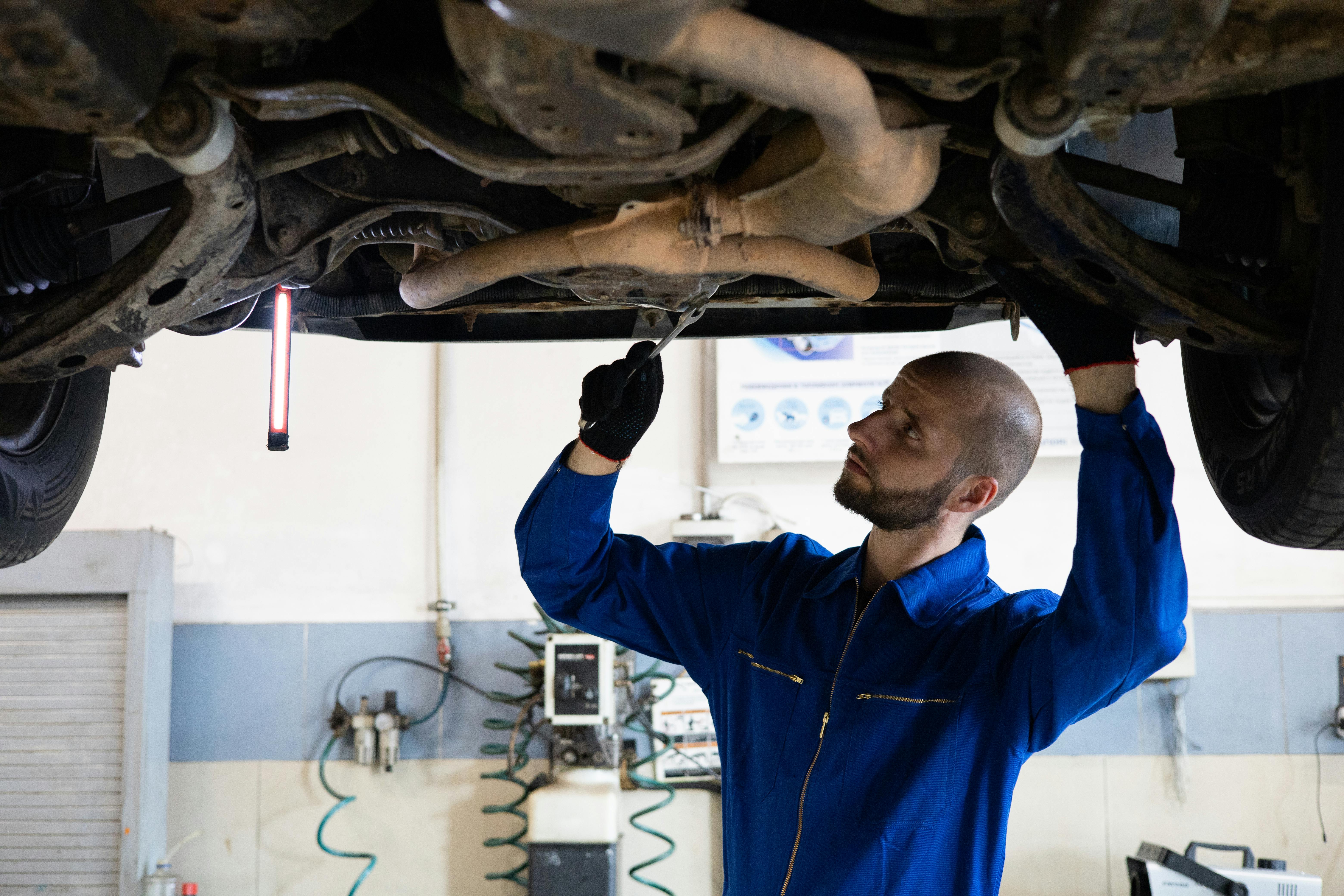 Mechanic inspecting vehicle exhaust system